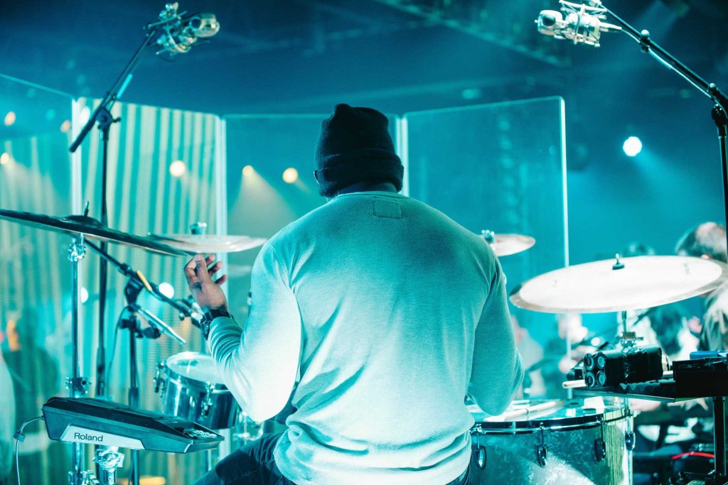 Drummer lifting his hands in prayer as part of the Engedi worship and production team.