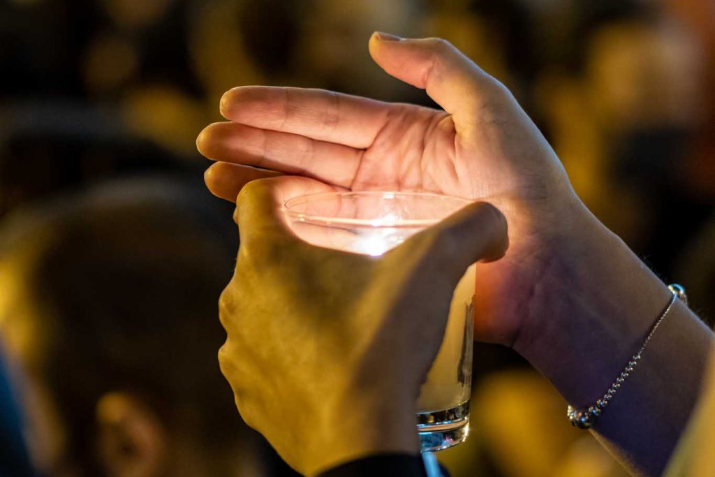 Hand holding a lighted candle at a demonstration of protesting people