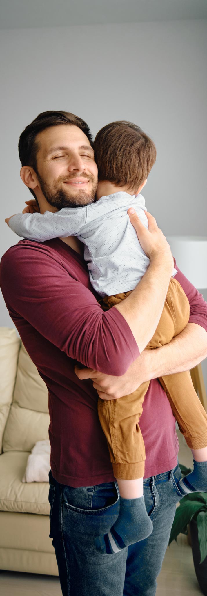 Young father enjoying with his son and embracing him at home.